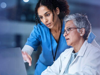 Arbeitende Person am Laptop mit Stift im Vordergrund 