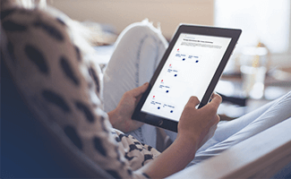 Patientin mit Tablet in der Hand im Wohnzimmer 
